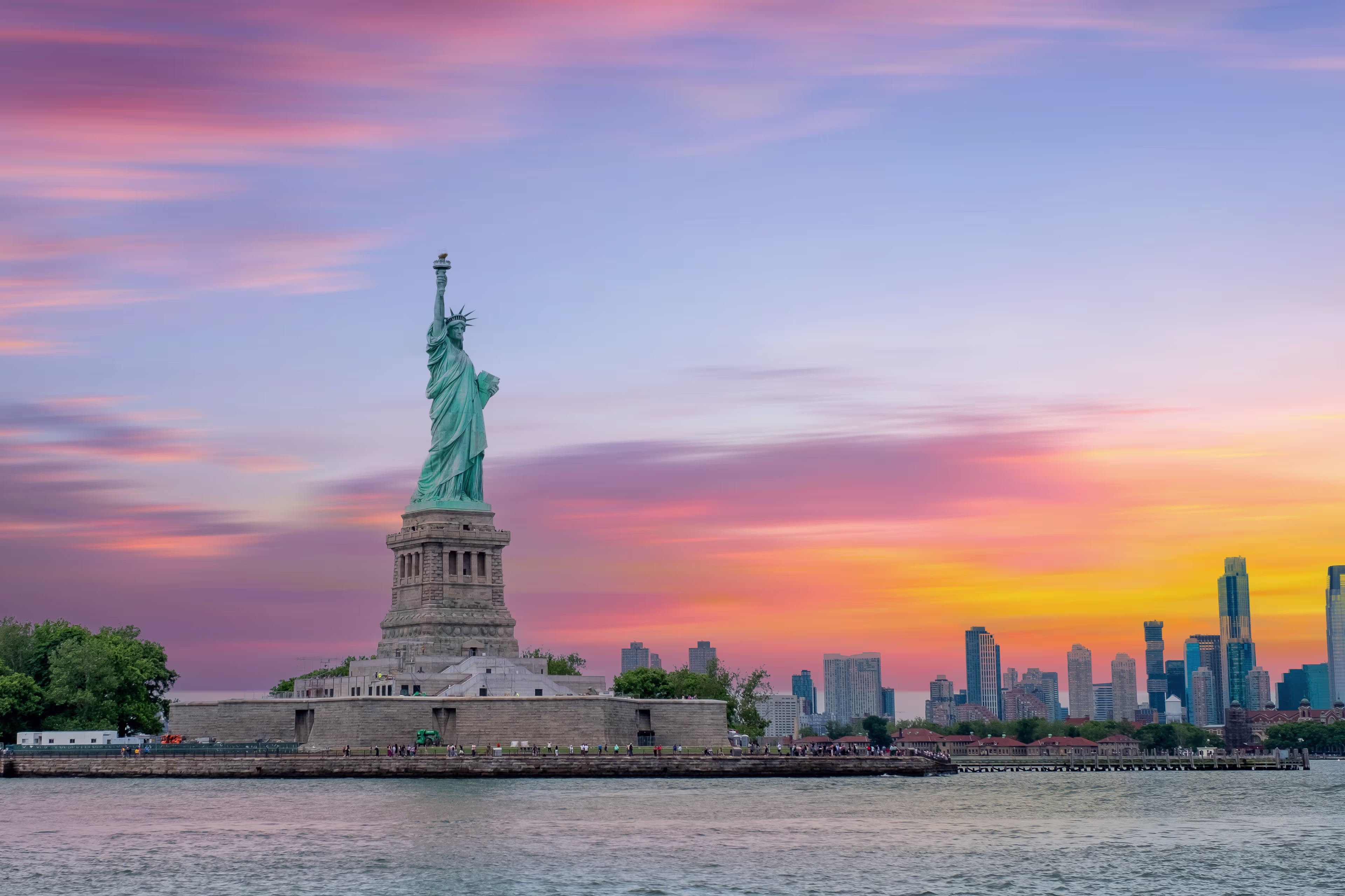Statue of Liberty with Lower Manhattan skyline at sunset